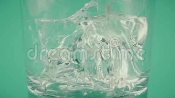 将棕色饮料倒入杯中在绿色背景下加入冰块慢镜头对准红色视频的预览图