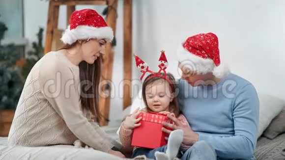 有趣的女婴开场礼物金球闪耀周围有可爱的爸爸妈妈视频的预览图