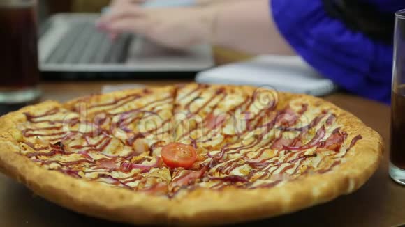 披萨在桌子上的盘子里女人手在后台的电脑键盘上打字重点转移视频的预览图