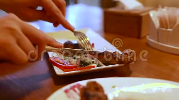 卢拉烤肉盘蔬菜在餐厅的木制桌子上男人切东西吃烤肉视频的预览图
