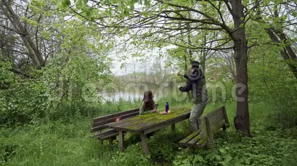 那个和那个女孩在一起的家伙正在从绿色公园的树上撕苹果旧木凳和桌子上面覆盖着视频的预览图