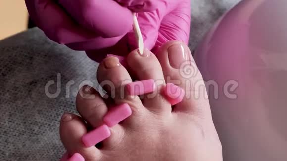 带粉色手套的教育学大师是用钻头在修脚沙龙切割角质层和紫胶脚趾甲视频的预览图