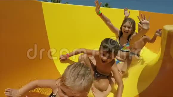 孩子们在水上公园里沿着橙色的滑梯滑下来视频的预览图