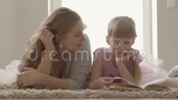 无忧无虑的金发白种人母亲和小女儿躺在床上一个漂亮的女人在向视频的预览图