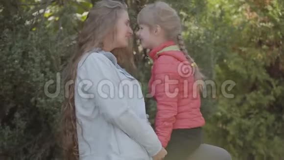 白种人女人留着长长的金发和她的小女孩在秋天公园里嬉戏妈妈和女儿视频的预览图