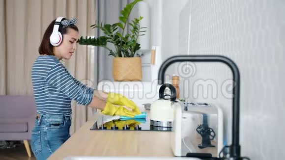 在厨房跳舞听耳机音乐的漂亮女孩在打扫卫生视频的预览图