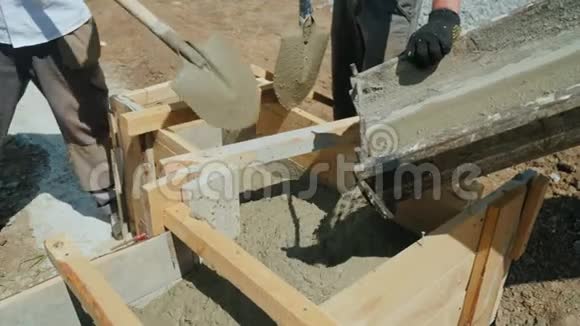 施工现场配合混凝土工作工人将混凝土放入木模中繁重的体力劳动视频的预览图