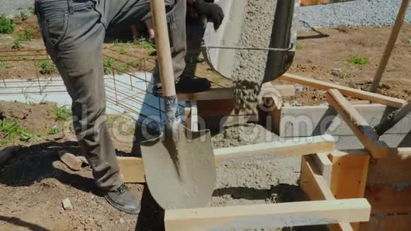 将混凝土浇筑成木模附近有一个拿着铲子的工人建造小屋视频的预览图