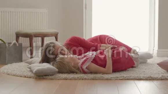 快乐的金发白种人母亲和小女儿在家里铺着蓬松的地毯的地板上聊天概念视频的预览图
