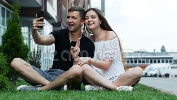 漂亮的年轻时尚夫妇在房子附近的草坪上自拍坐在草地上视频的预览图
