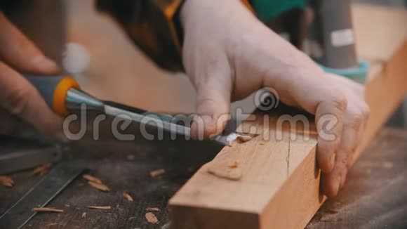 木工一个木工用凿子把木块上的凹槽凿出来一个没有手套的人工作视频的预览图
