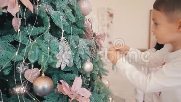 可爱的小男孩把星星玩具挂在圣诞树上视频的预览图