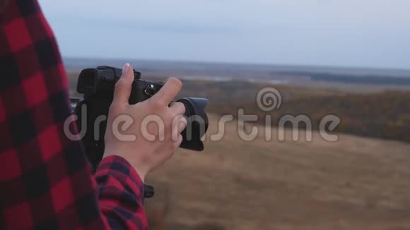 年轻独立女旅游摄影师用专业数码相机拍摄美丽的秋景视频的预览图