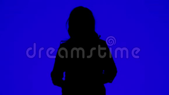 一位女士戴着耳机在蓝色背景下随着音乐起舞的剪影视频的预览图