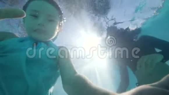 小女孩游过镜头看着它和棕榈树的天空背景视频的预览图