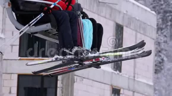 滑雪者乘坐滑雪电梯带滑雪板和滑雪靴的腿在森林的雪松的背面视频的预览图