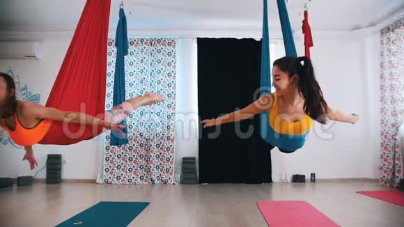 空中瑜伽两个女人躺在吊床上在吊床上摆动互相看着对方视频的预览图