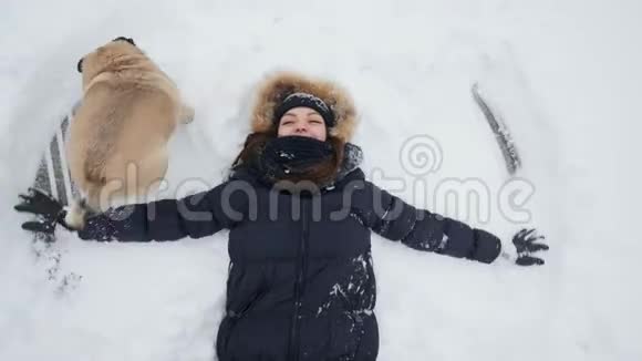 顶部风景快乐的女人做雪天使她的小狗跑着跳着视频的预览图