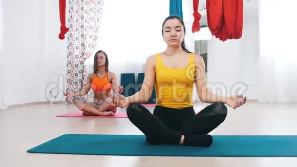 瑜伽两个冷静的女人坐在垫子上做呼吸练习视频的预览图