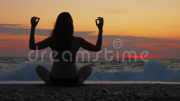 一位年轻女性在日落时在海边或海边练习瑜伽视频的预览图
