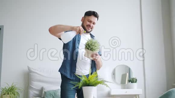 慢动作的微笑的家伙把房子的花洒在花盆里照顾植物视频的预览图