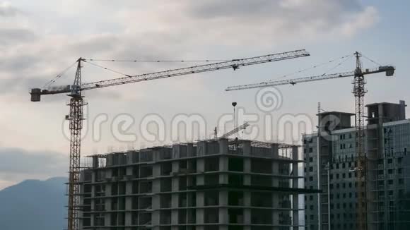 建筑工地上的塔式起重机在高层建筑中提升负荷时光流逝建筑工程视频的预览图