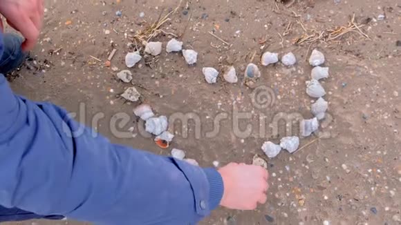 人类正在用海沙滩上的贝壳做心脏双手特写视频的预览图