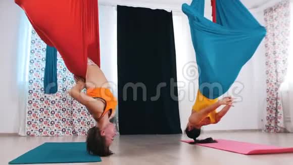 空中瑜伽两个女人倒挂在吊床上双腿伸直视频的预览图