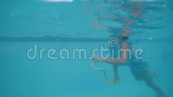 小女孩在游泳池游泳手拿玩具滑雪在热带酒店侧视视频的预览图