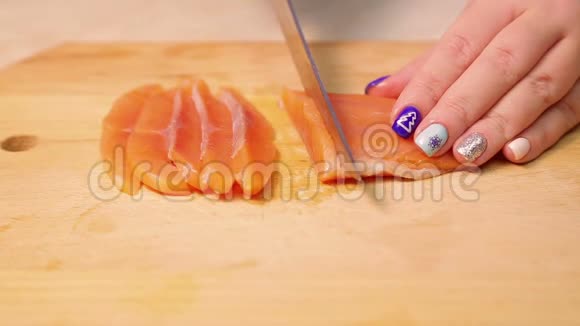 女性手在木板上切红鳟鱼做三明治视频的预览图