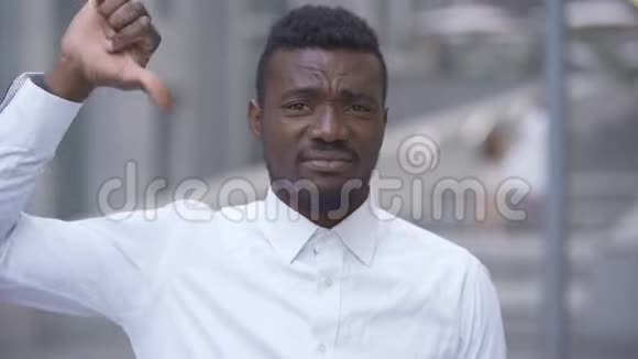 一位身穿白衬衫的非洲裔美国帅哥站在城市里向镜头竖起大拇指的特写镜头视频的预览图