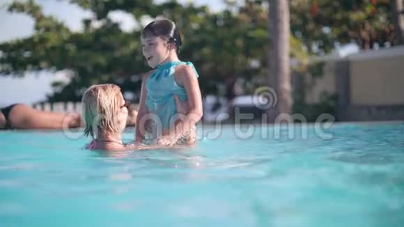 妈妈正在游泳池里和孩子女儿玩把她扔到空中和潜水视频的预览图