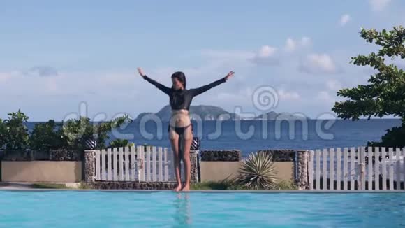 亚洲女孩在热带海山背景下在游泳池附近做伸展运动视频的预览图