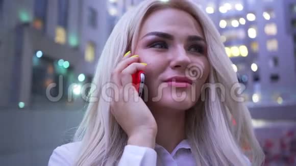 穿着白色夹克的迷人自信的女人站在城市街道上用手机说话女商人视频的预览图