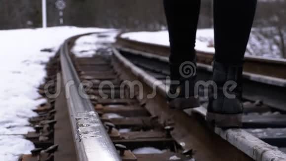 一个女孩的腿在冬天沿着旧铁路轨道行走慢动作视频的预览图