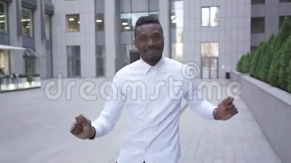 快乐快乐的非裔美国人穿着白色衬衫在城市街道上的现代商务中心前跳舞男性视频的预览图