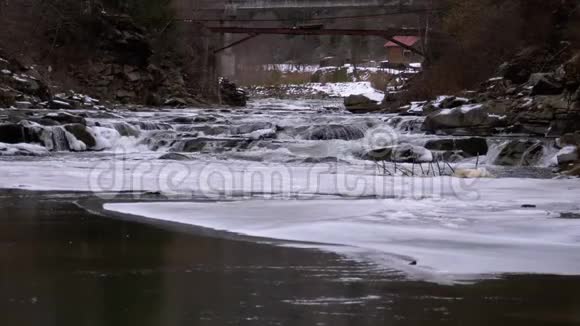 冬天雪从山溪和石急流中快速流出的水瀑布慢动作视频的预览图