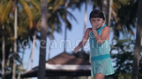 微笑的小女孩穿着湿衣服在热带度假胜地的泳池边散步视频的预览图