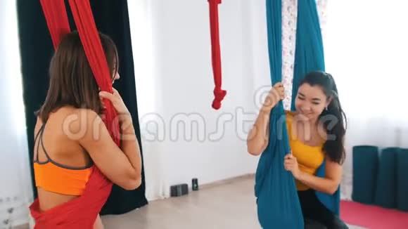 空中瑜伽两个运动的女人坐在吊床上互相交谈视频的预览图