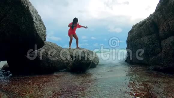 一位女士正幸福地站在海边的岩石上视频的预览图