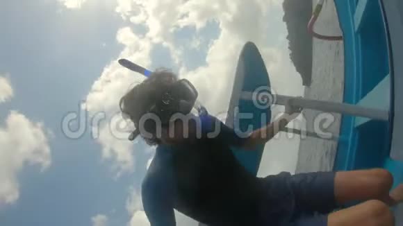 戴着潜水面罩的人从一艘船上跳到海里去看努萨佩尼达岛上的曼塔点的曼塔视频的预览图