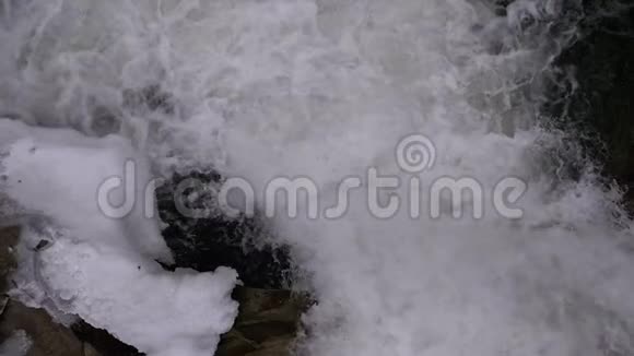 山溪和石急流与雪水的快速流动冬季瀑布慢动作视频的预览图