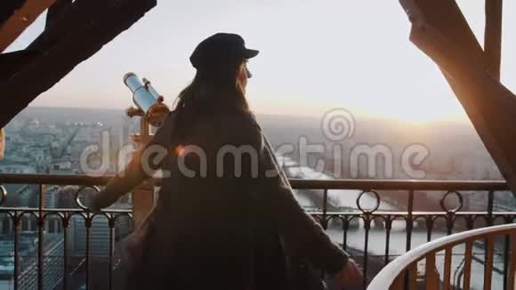 美丽的年轻女子在埃菲尔铁塔顶部摆姿势和旋转欣赏史诗般的日落巴黎天空全景慢动作视频的预览图