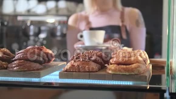 糖果店的新鲜糕点焦点从一个陈列柜上的烘焙转变为一个持咖啡的女售货员视频的预览图