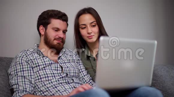 一对年轻貌美的夫妇坐在沙发上上网购物视频的预览图