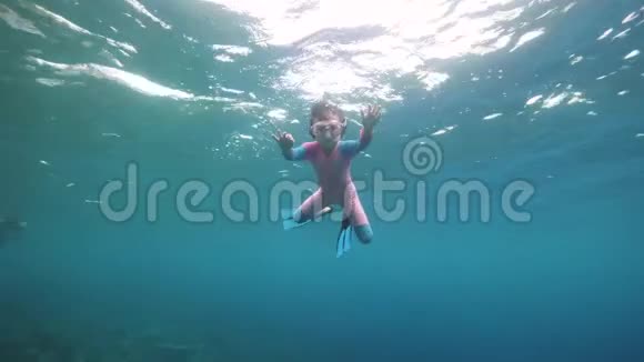 一个勇敢的小女孩独自在蓝色的深海里游泳和潜水视频的预览图