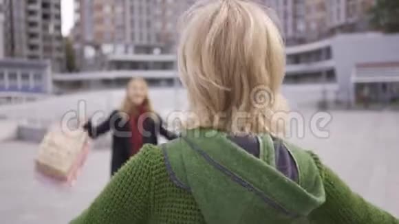 两个金发白种人女孩在购物后在街上相遇两个时尚女人拥抱他们很高兴看到视频的预览图