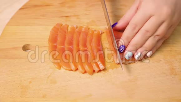 雌性手在木板上切红鳟鱼做三明治视频的预览图