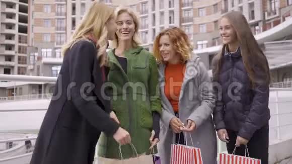 四个快乐的漂亮女孩带着购物袋享受着她们的购买竖起大拇指休闲在一起视频的预览图