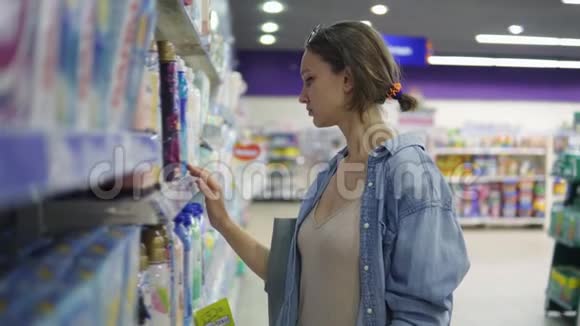 年轻漂亮的女士在一家超市随便检查商品读取产品上的标签挑选洗过的衣服视频的预览图